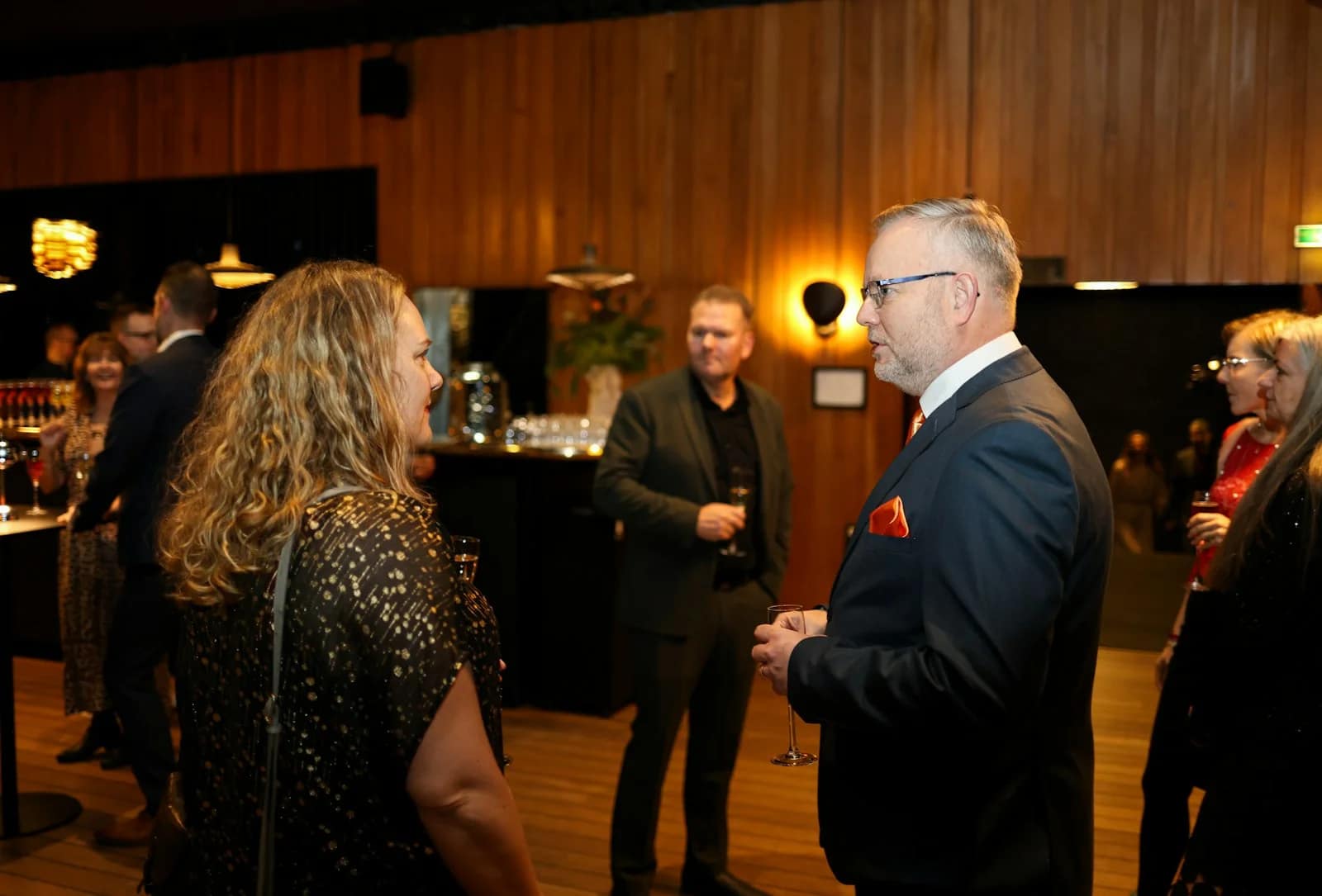 People mingling at a formal event with drinks People mingling at a formal event with drinks